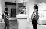 在大都会博物馆，两个学生在看一个用玻璃包装的花瓶